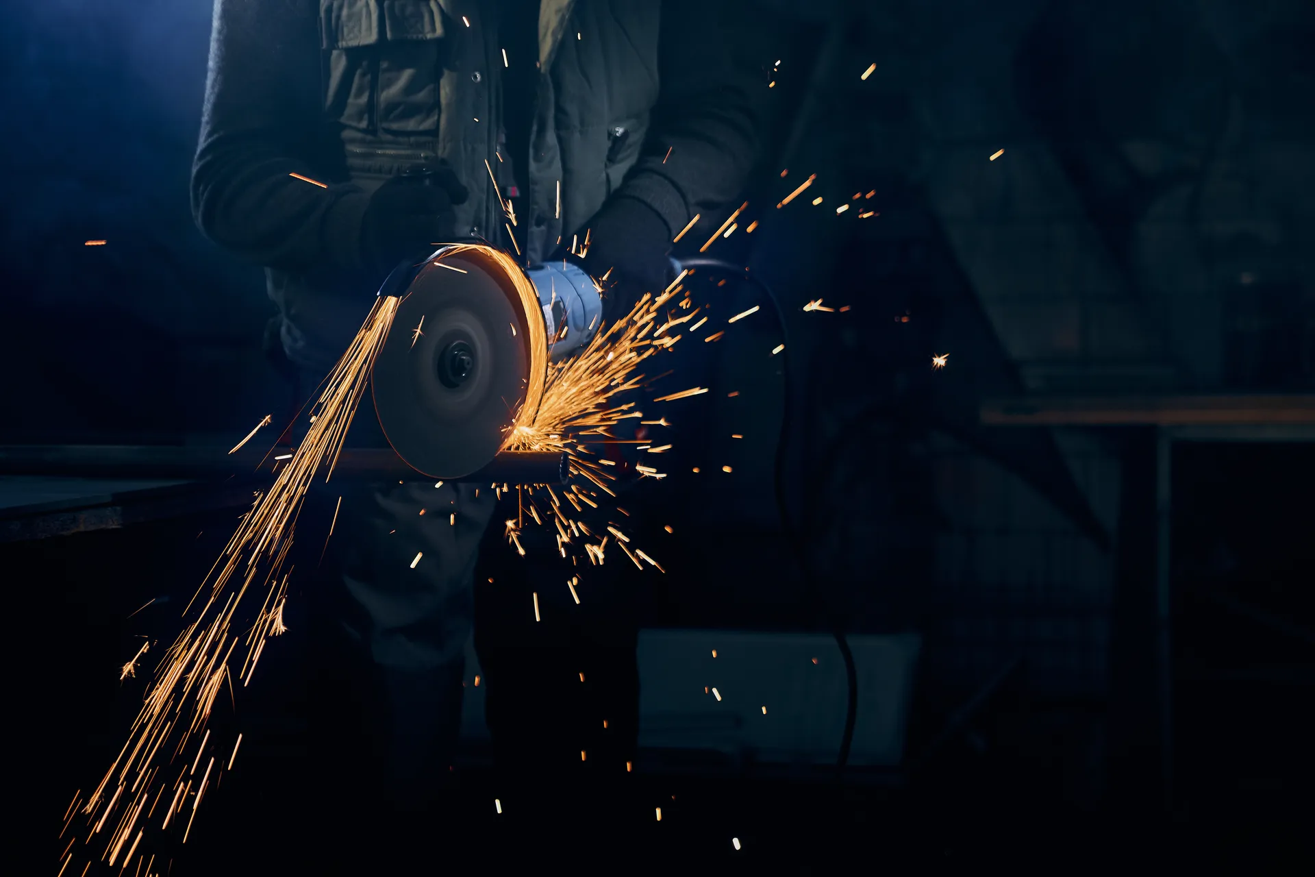Worker angle grinding a metal surface with sparks