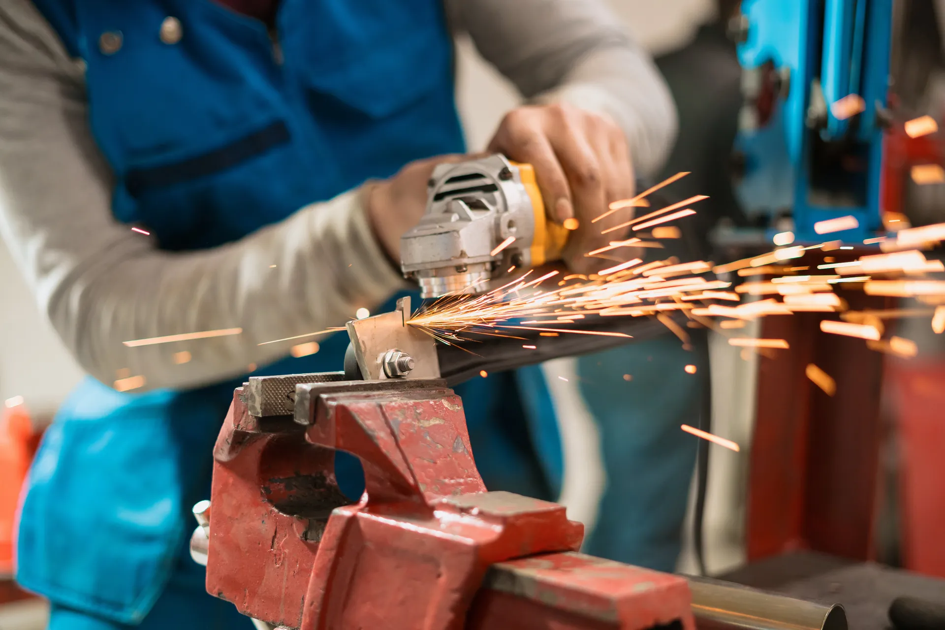Worker grinding metal on the factory floor with sparks flying