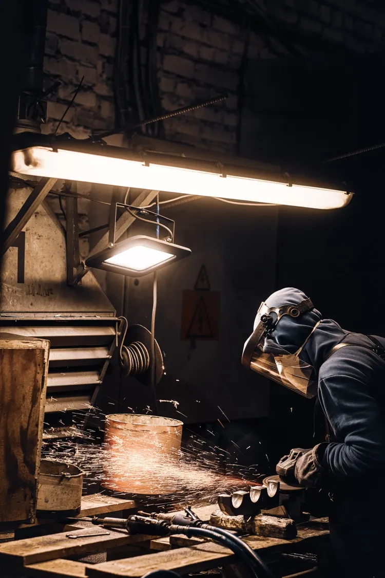 Professional welder in full protective gear in workshop
