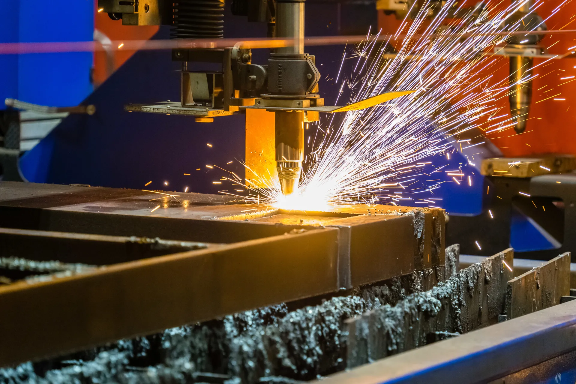 Plasma torch cutting through a steel beam with sparks