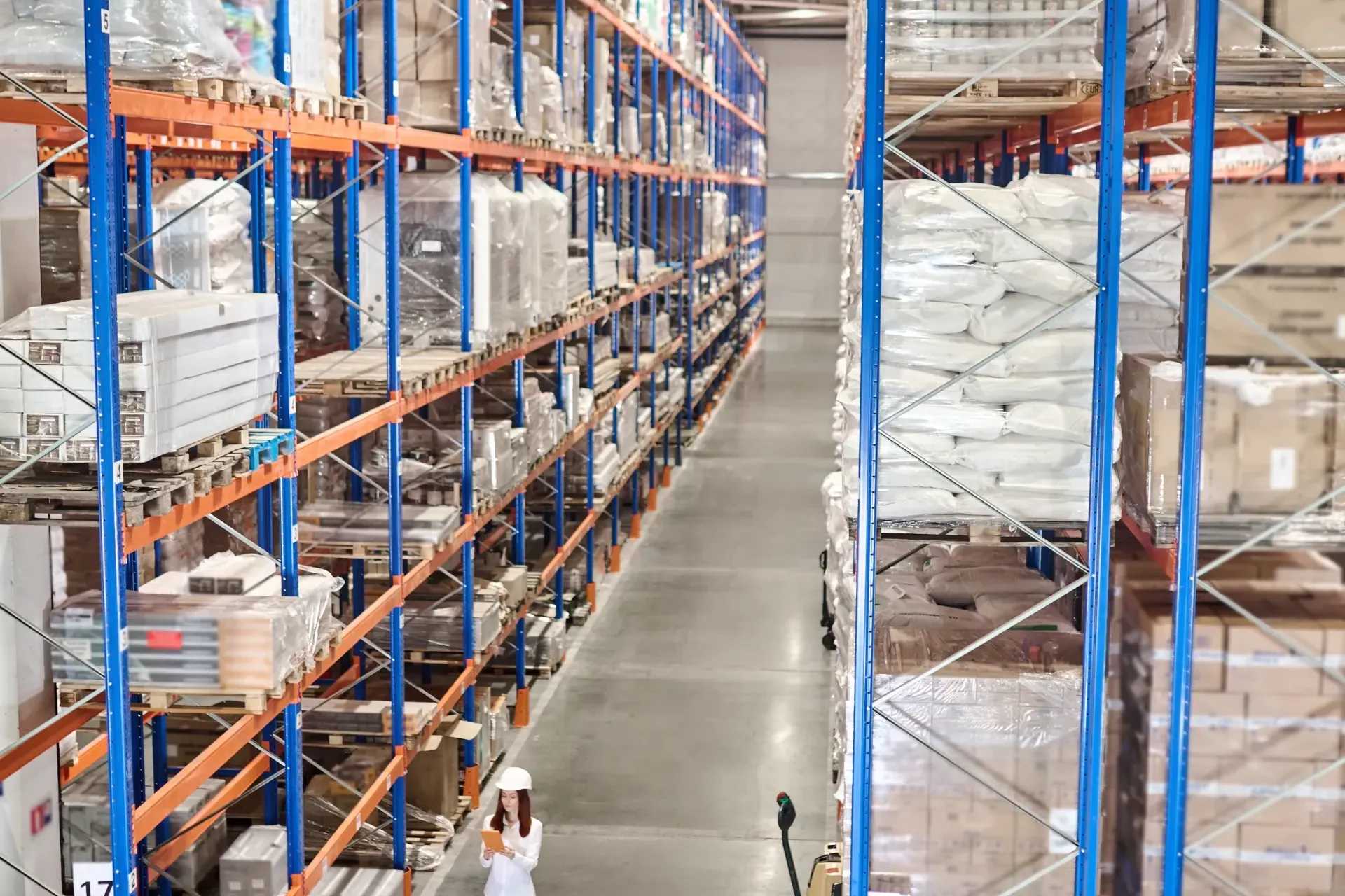 Warehouse supervisor checking inventory on a tablet between storage racks