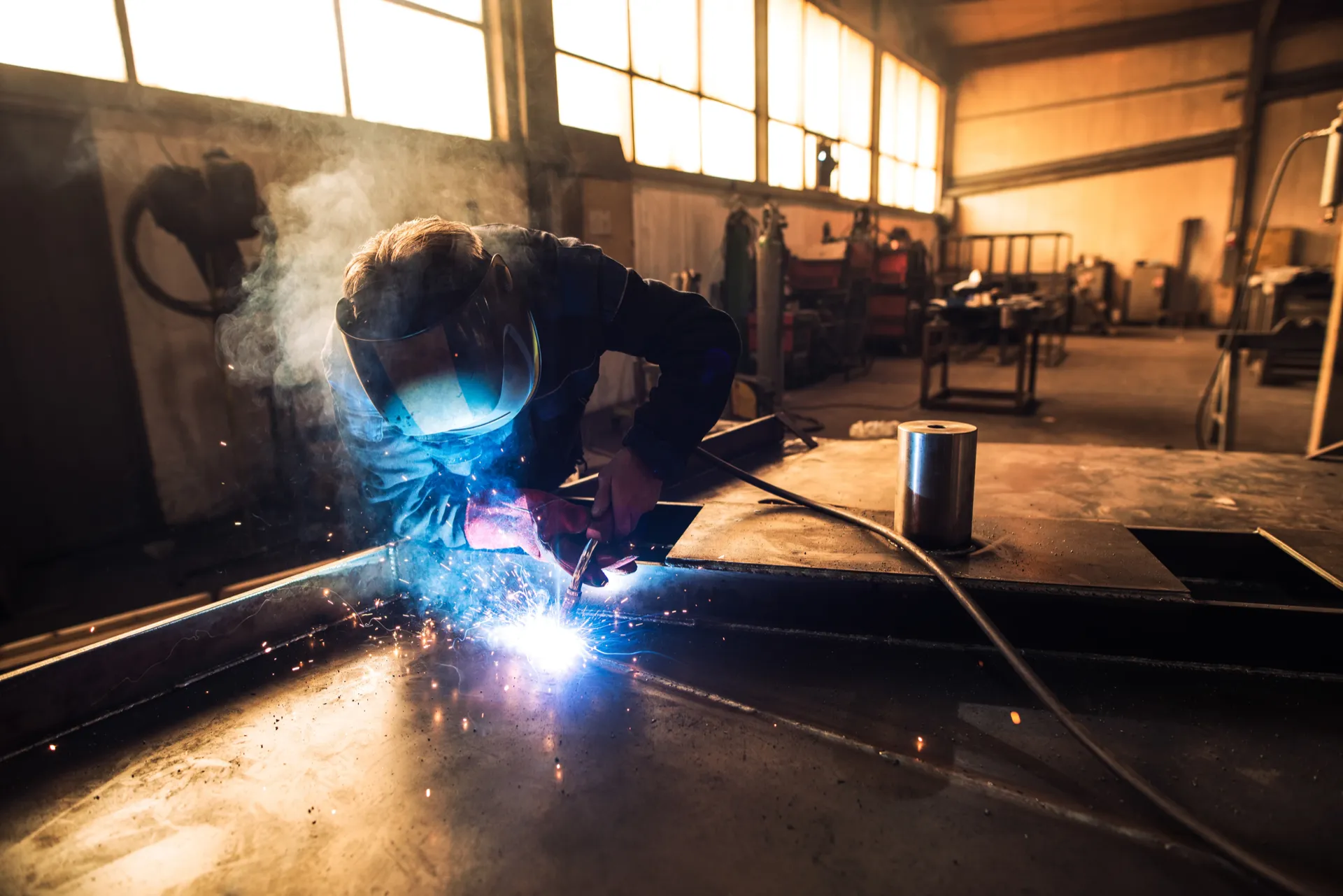 Professional welder in full protective gear in workshop