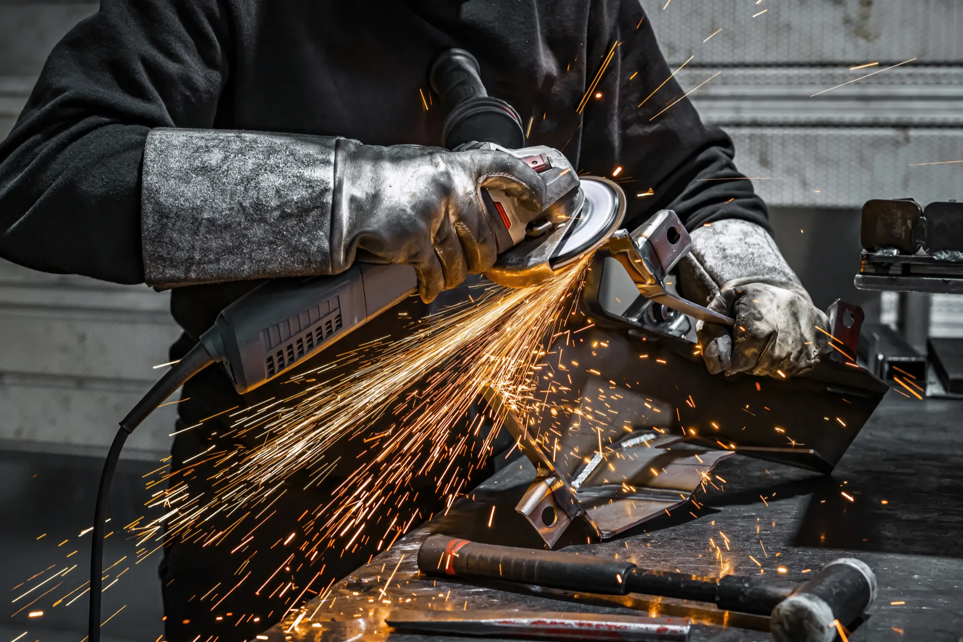 Worker grinding a metal piece with sparks